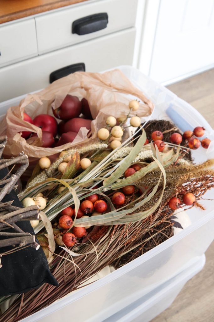 A picture of faux fall stems in a storage tote.