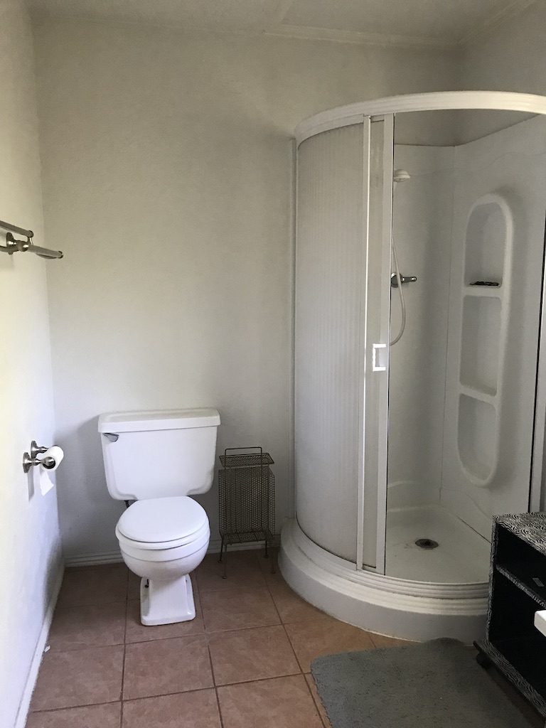 A picture of a dated master bathroom with a toilet and corner shower. 
