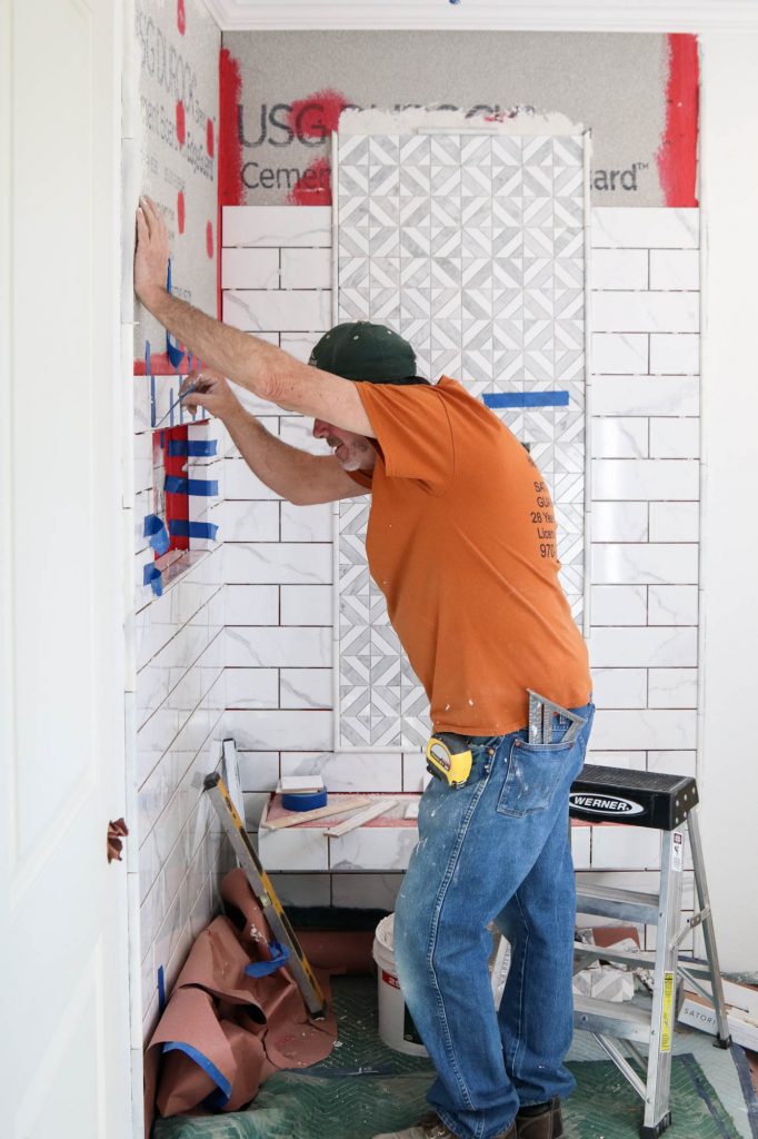 A picture of our contractor installing shower tile.