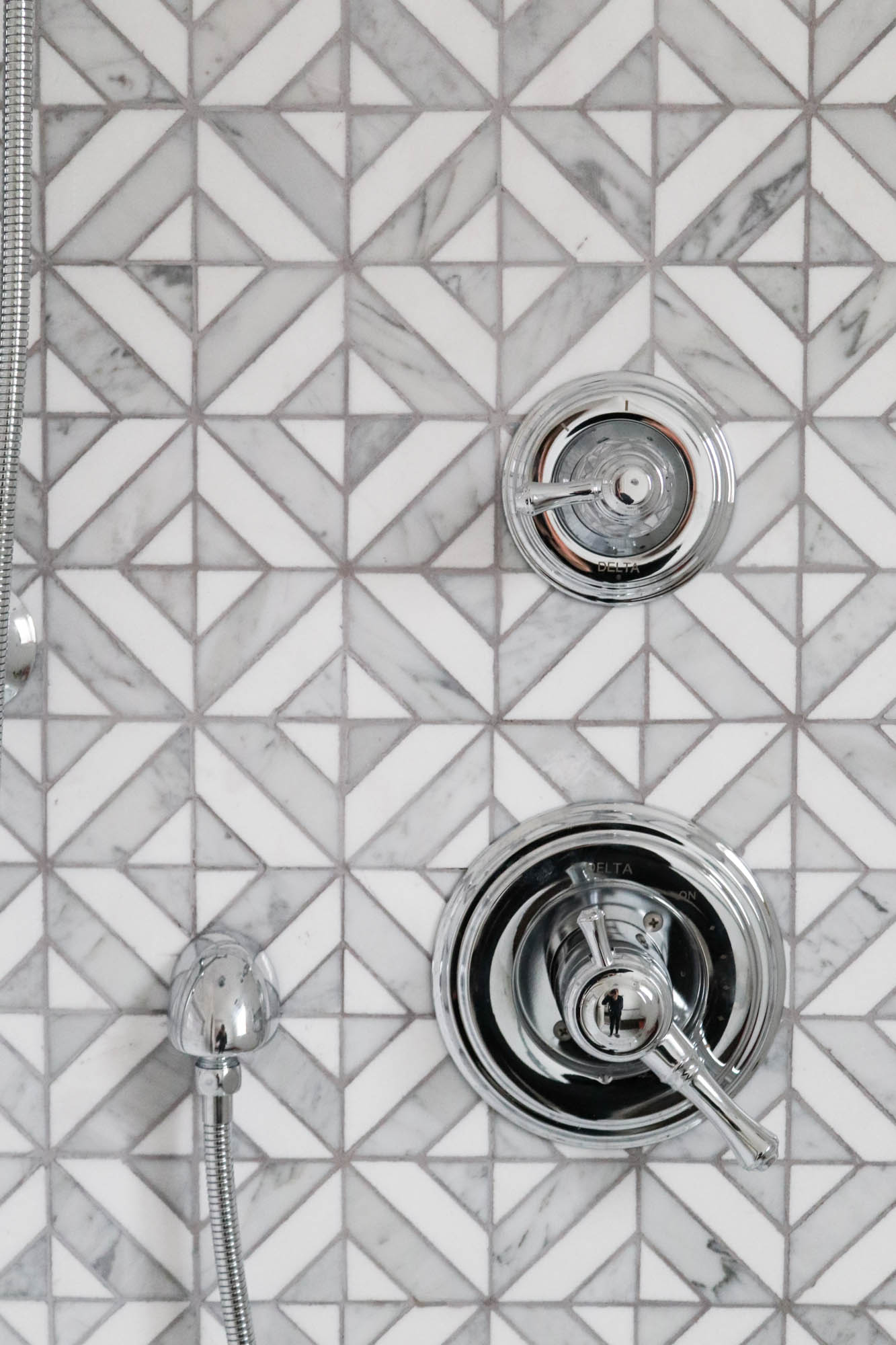 A picture of the shower tile and plumbing fixtures.
