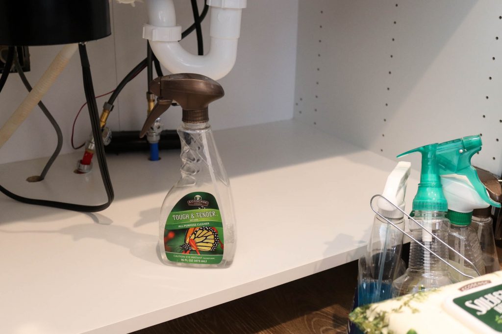 A picture showing the first step of organizing under the kitchen sink: removing everything and cleaning the cabinet. 