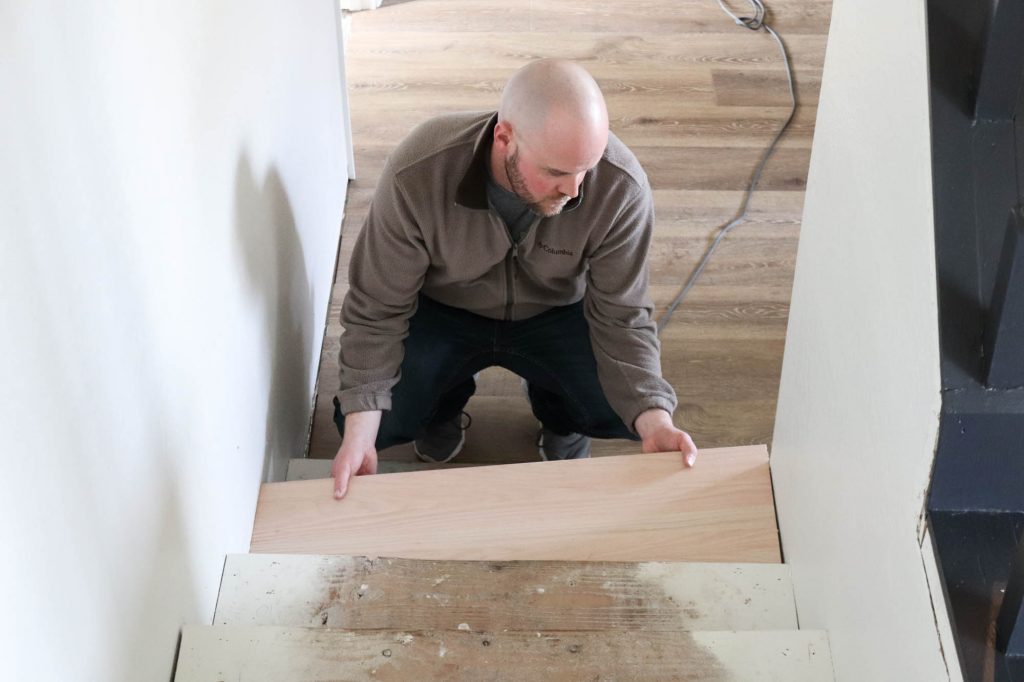 A picture of Todd placing the new stair tread on the step. 