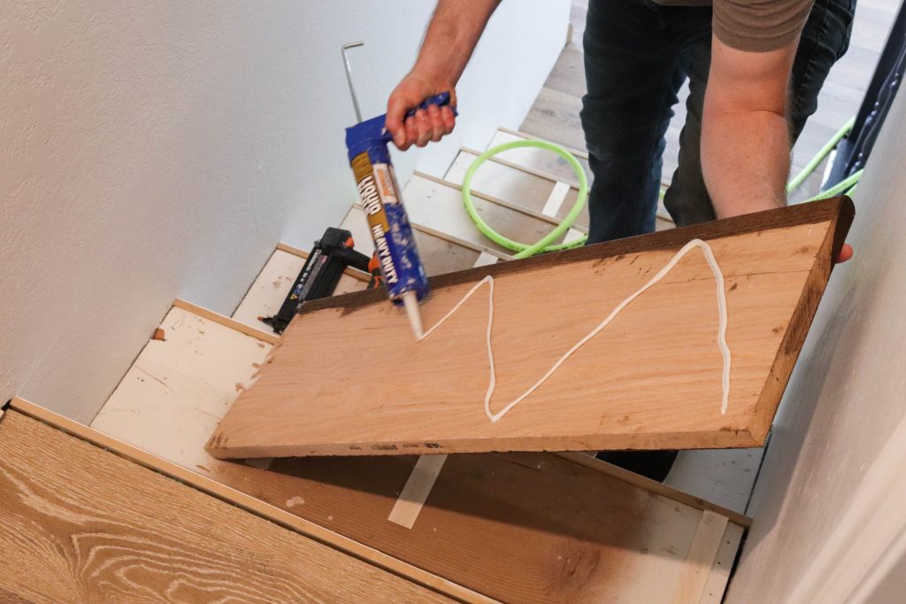 A picture of Todd applying liquid nails to the back of the stair tread. 