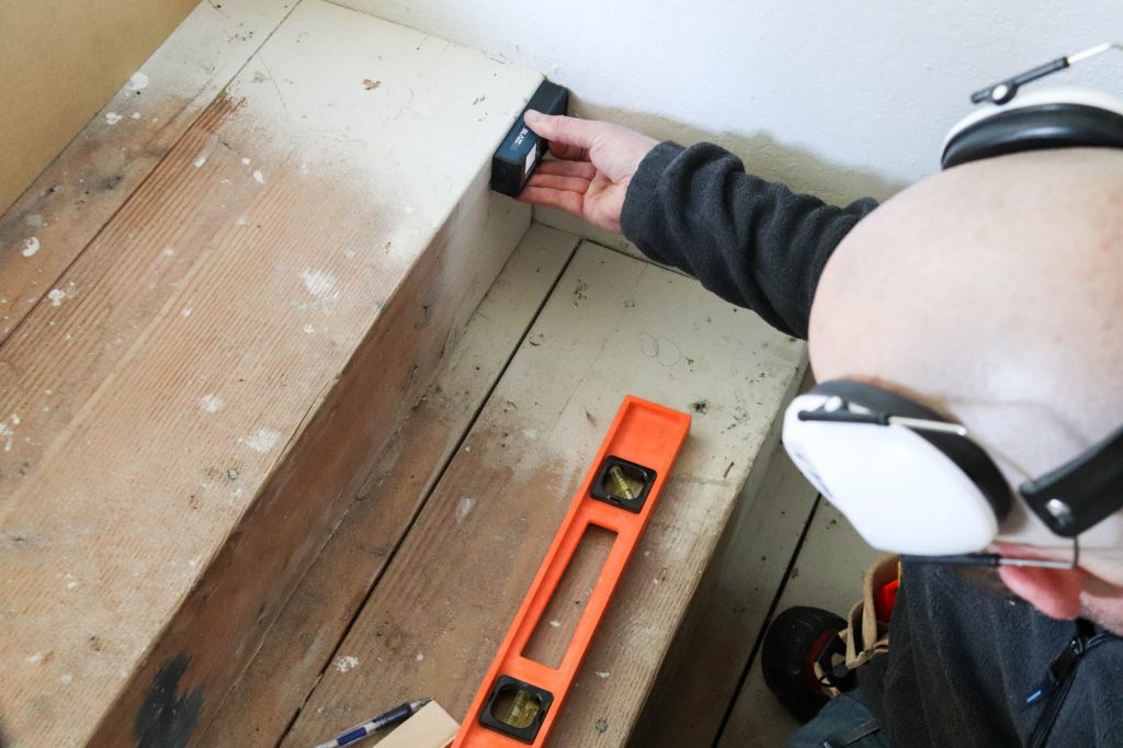 A picture of Todd measuring each stair riser to be covered. 