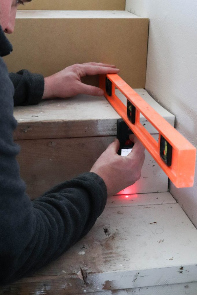 A picture of Todd measuring each stair riser to be covered. 