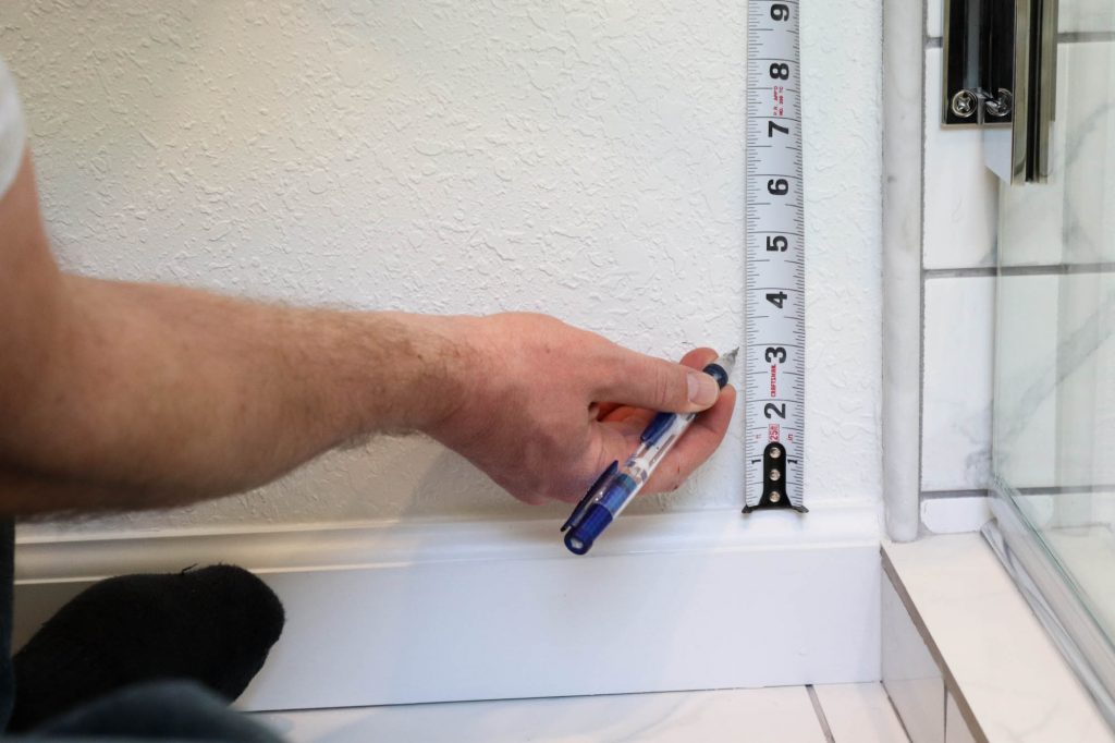 A picture showing Todd measuring up the wall 3". 