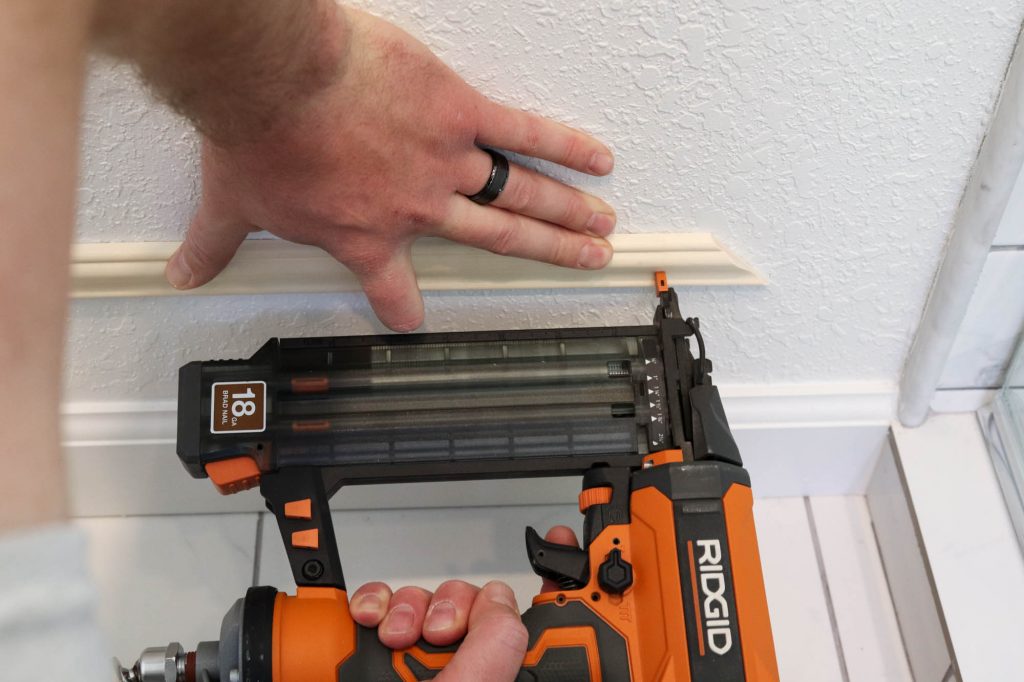 A picture of Todd nailing the moulding onto the wall.