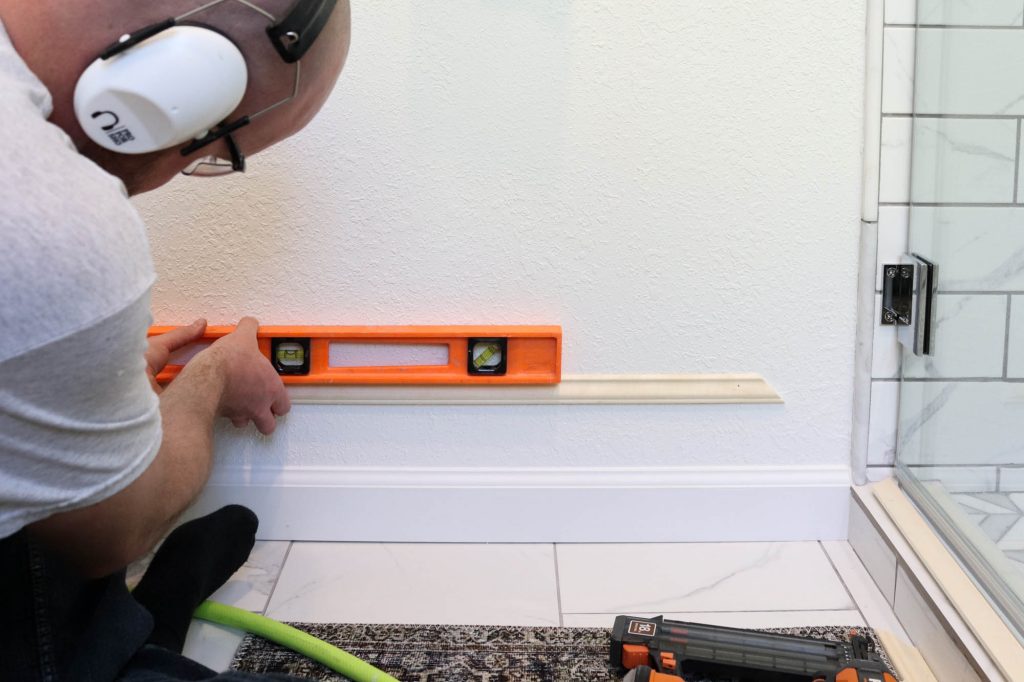 A picture of Todd using a level to make sure the moulding strip is level.