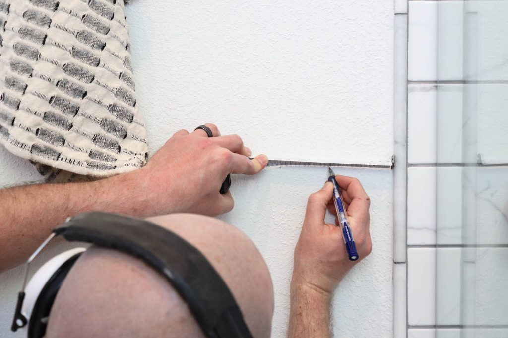 A picture of Todd measuring 3" over from the edge of the tile.