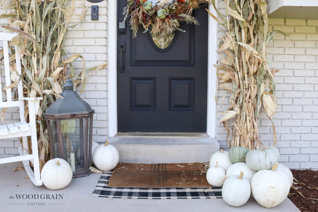 A picture of our front porch with cornstalks, white pumpkins and a lantern.