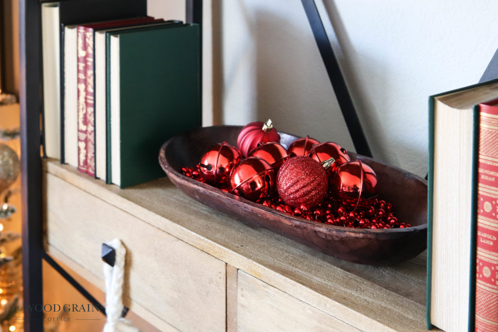 A picture of red Christmas ornaments in a wooden bowl. 