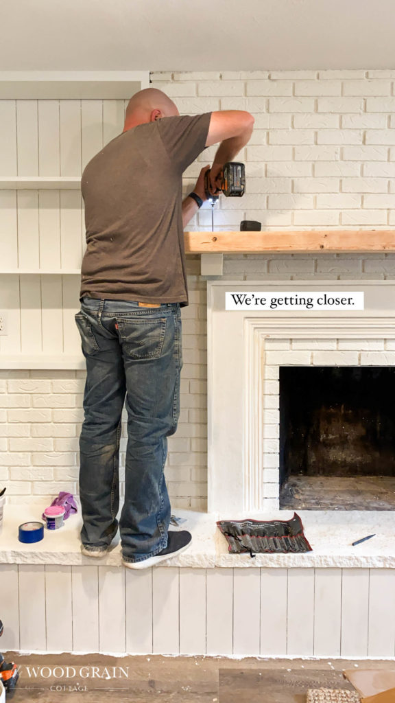 A picture of Todd installed the freshly sanded mantel. 